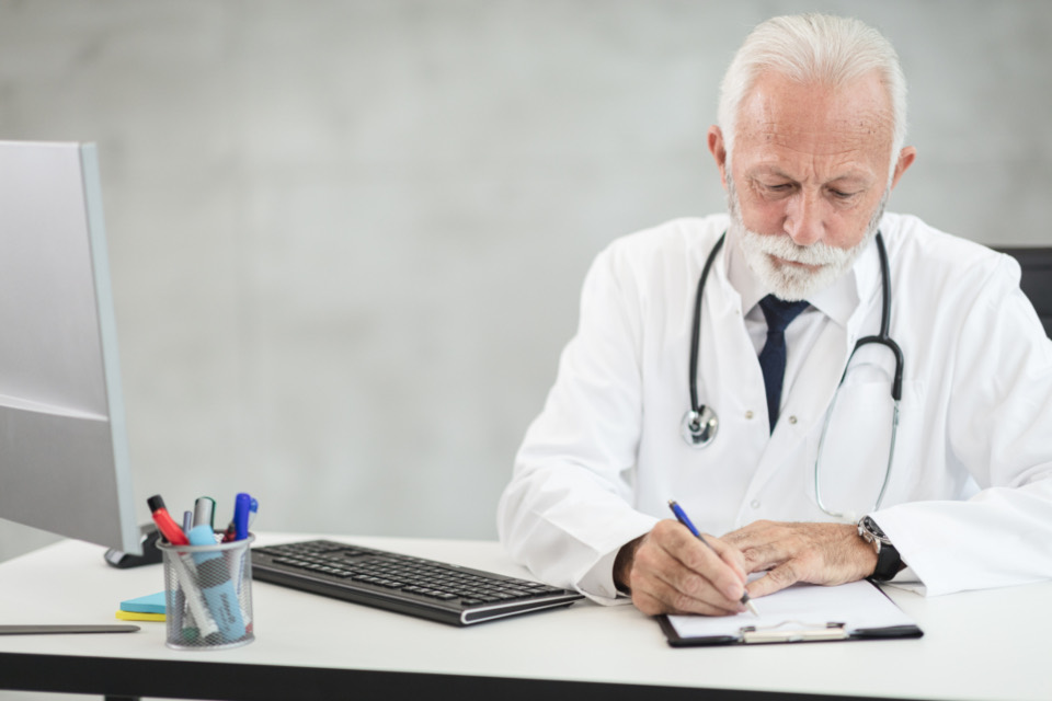 A clinician in a white coat working at a desk